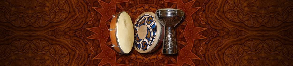 A frame drum, a bodhran, and a dumbek in front of a carved wooden mandala.